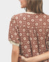 Woman wearing a patterned blouse with a neutral background