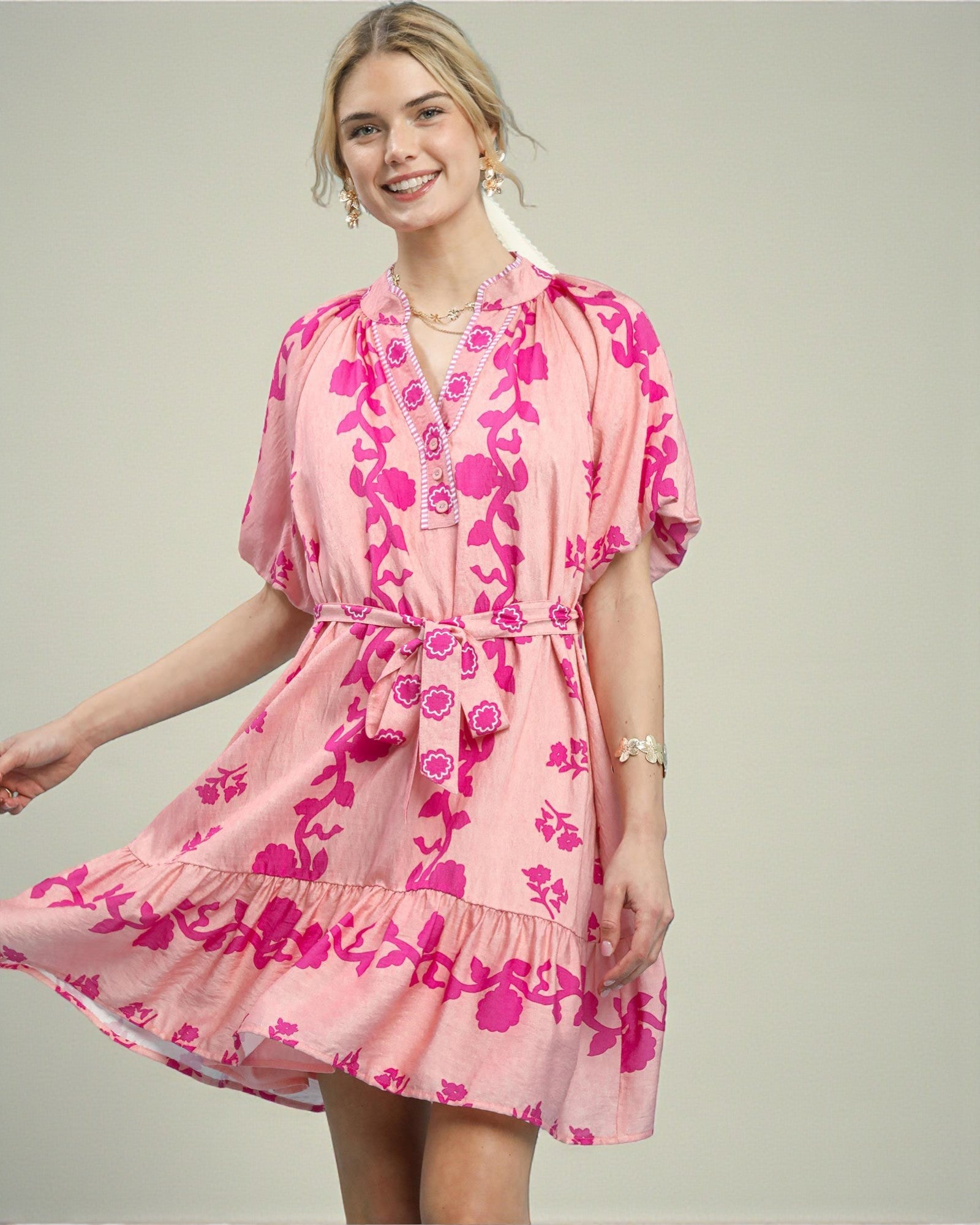 Woman wearing a pink floral dress against a plain background