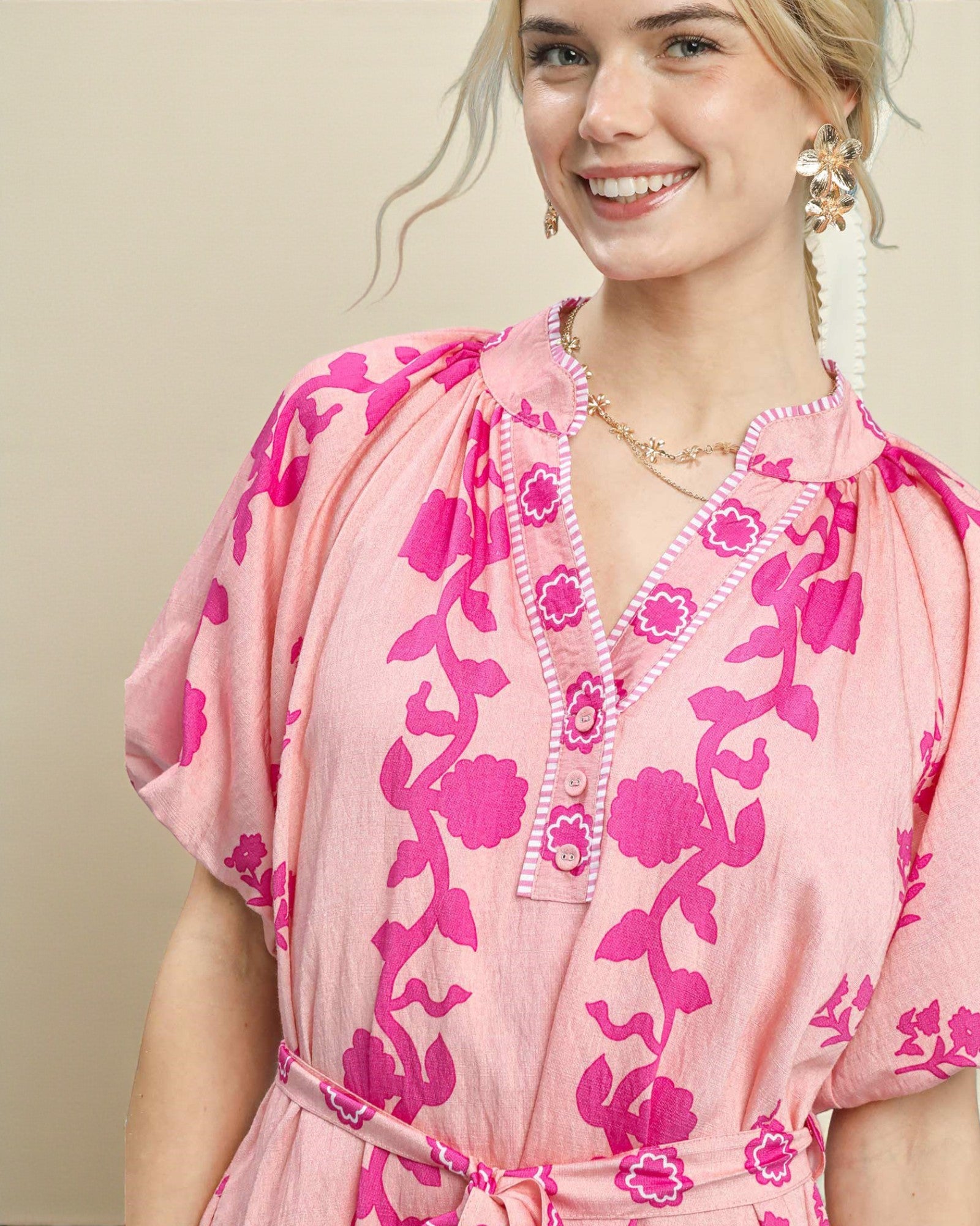 Woman wearing a pink floral dress against a beige background