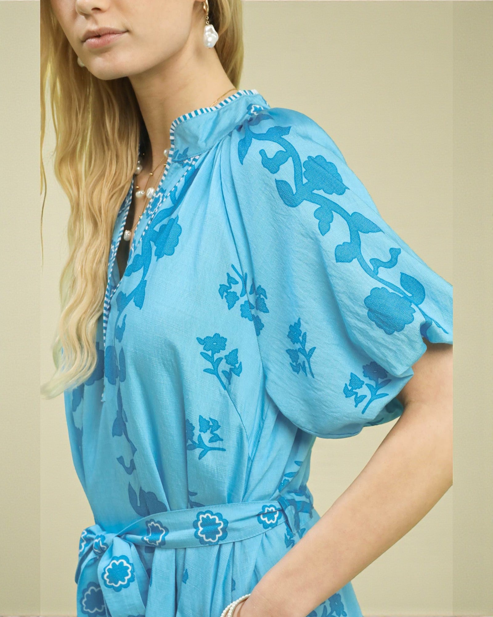 Woman wearing a blue floral dress against a beige background