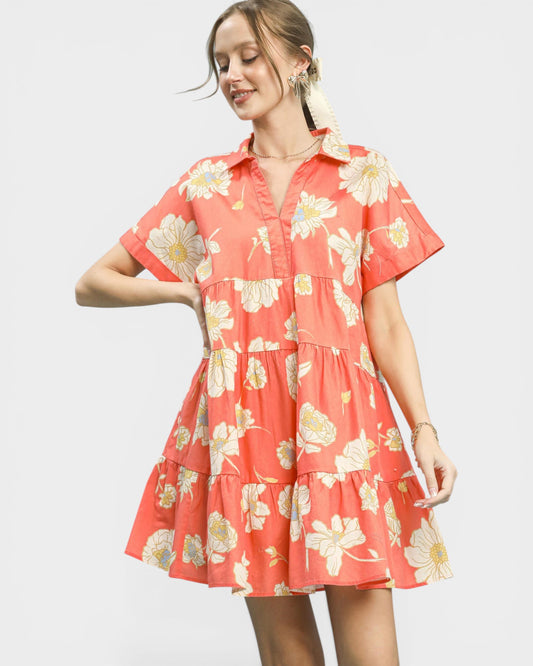 Woman wearing a coral floral dress on a light gray background