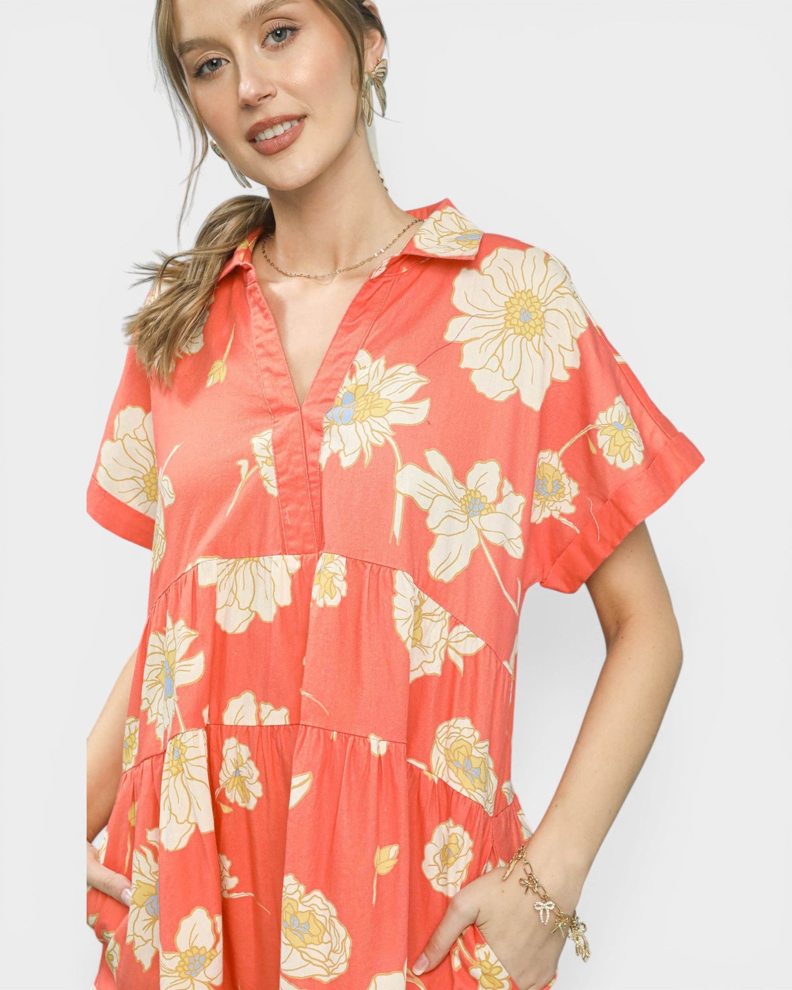 Woman wearing a coral dress with floral pattern on a white background