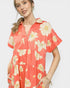 Woman wearing a coral dress with floral pattern on a white background