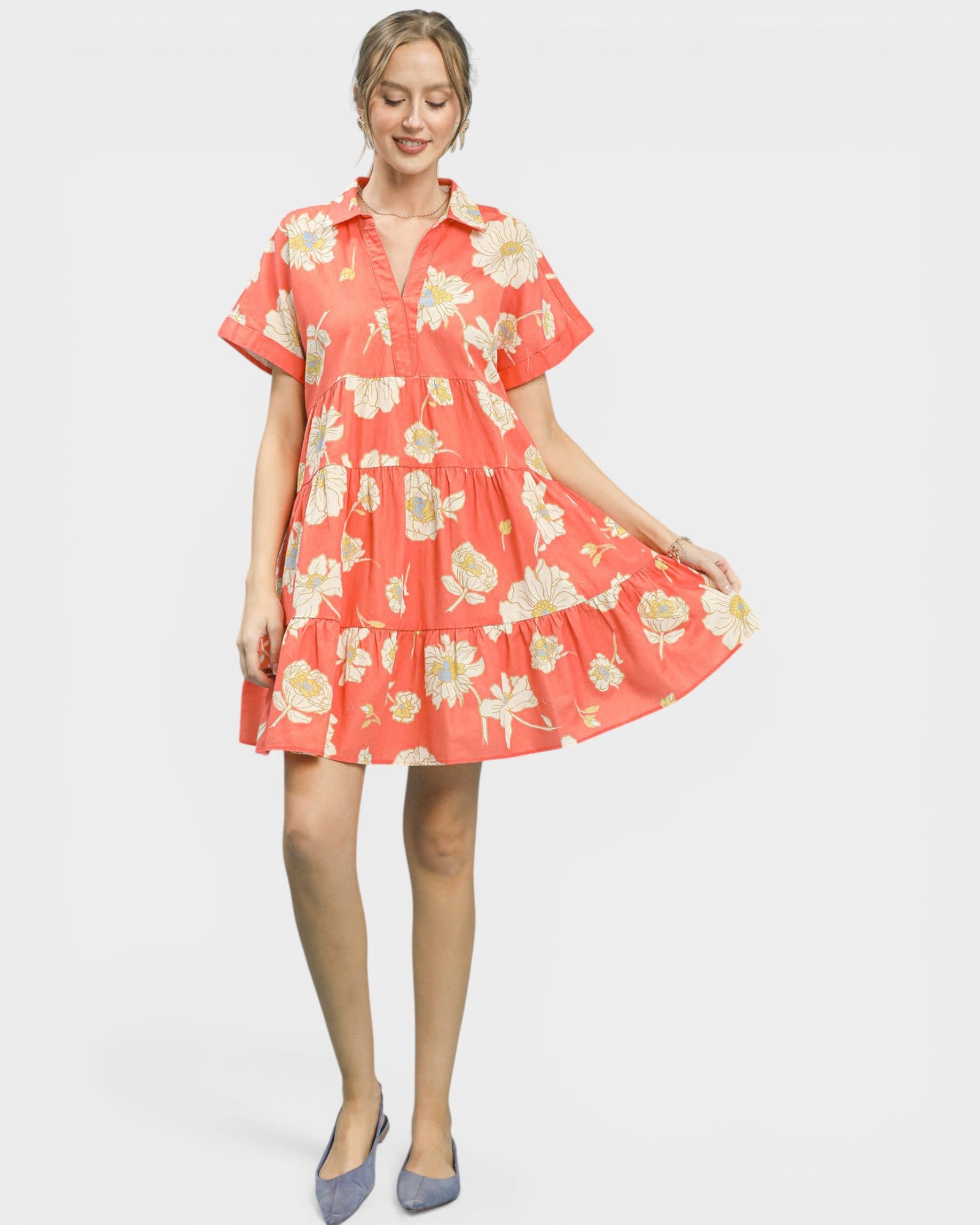 Woman wearing a coral floral dress on a white background
