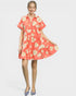Woman wearing a coral floral dress on a white background