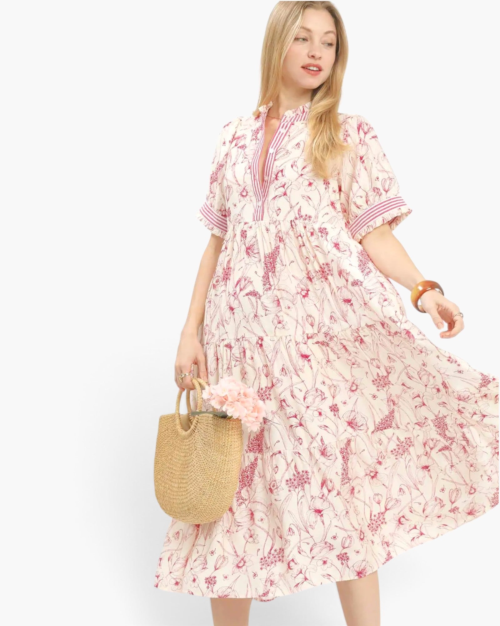 A woman modeling a short-sleeve midi dress with a pink and red abstract floral print on a cream background.