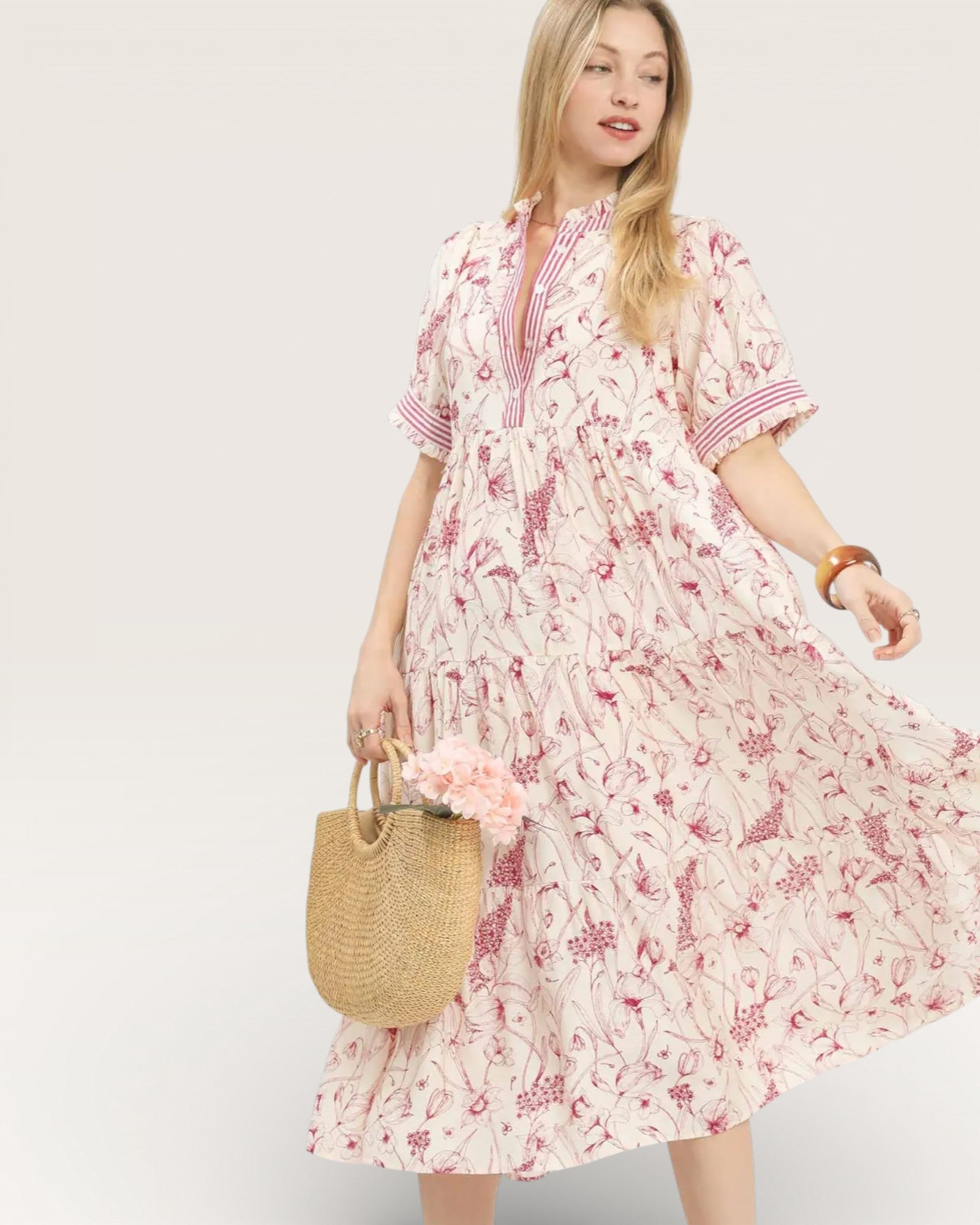 Woman wearing a floral dress holding a straw bag on a plain background