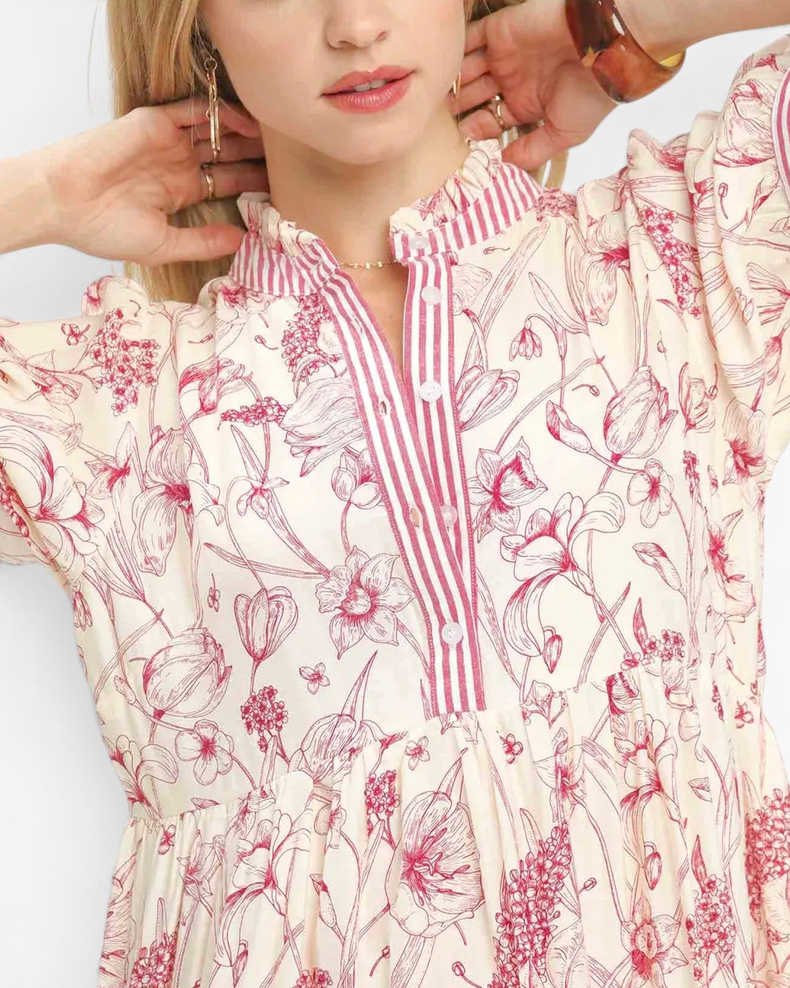 A woman modeling a short-sleeve midi dress with a pink and red abstract floral print on a cream background.