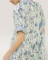 Person wearing a blue and white floral patterned dress on a plain background