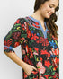 Woman wearing a colorful floral dress with a plain background