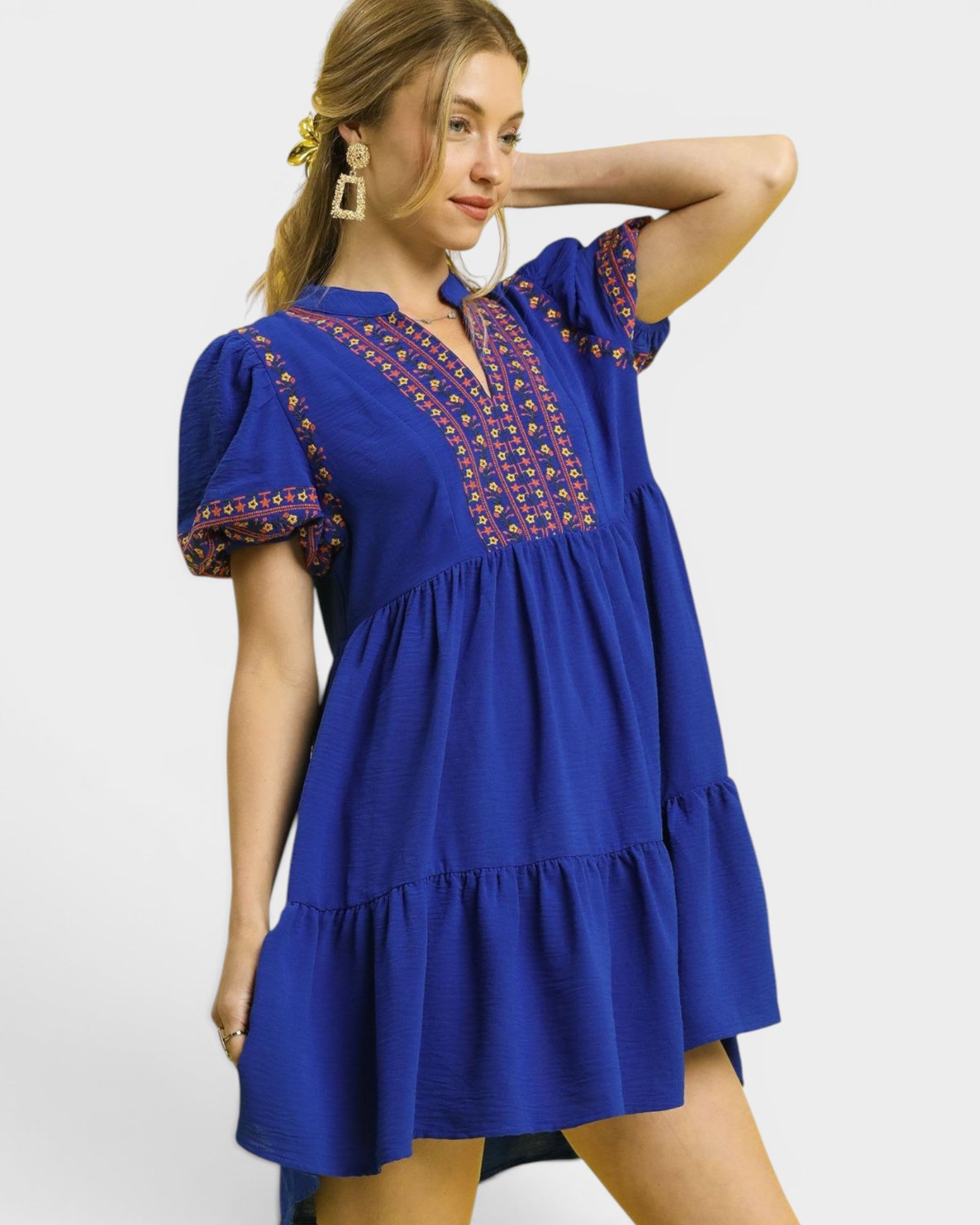 Woman wearing a blue dress with intricate patterns on a white background