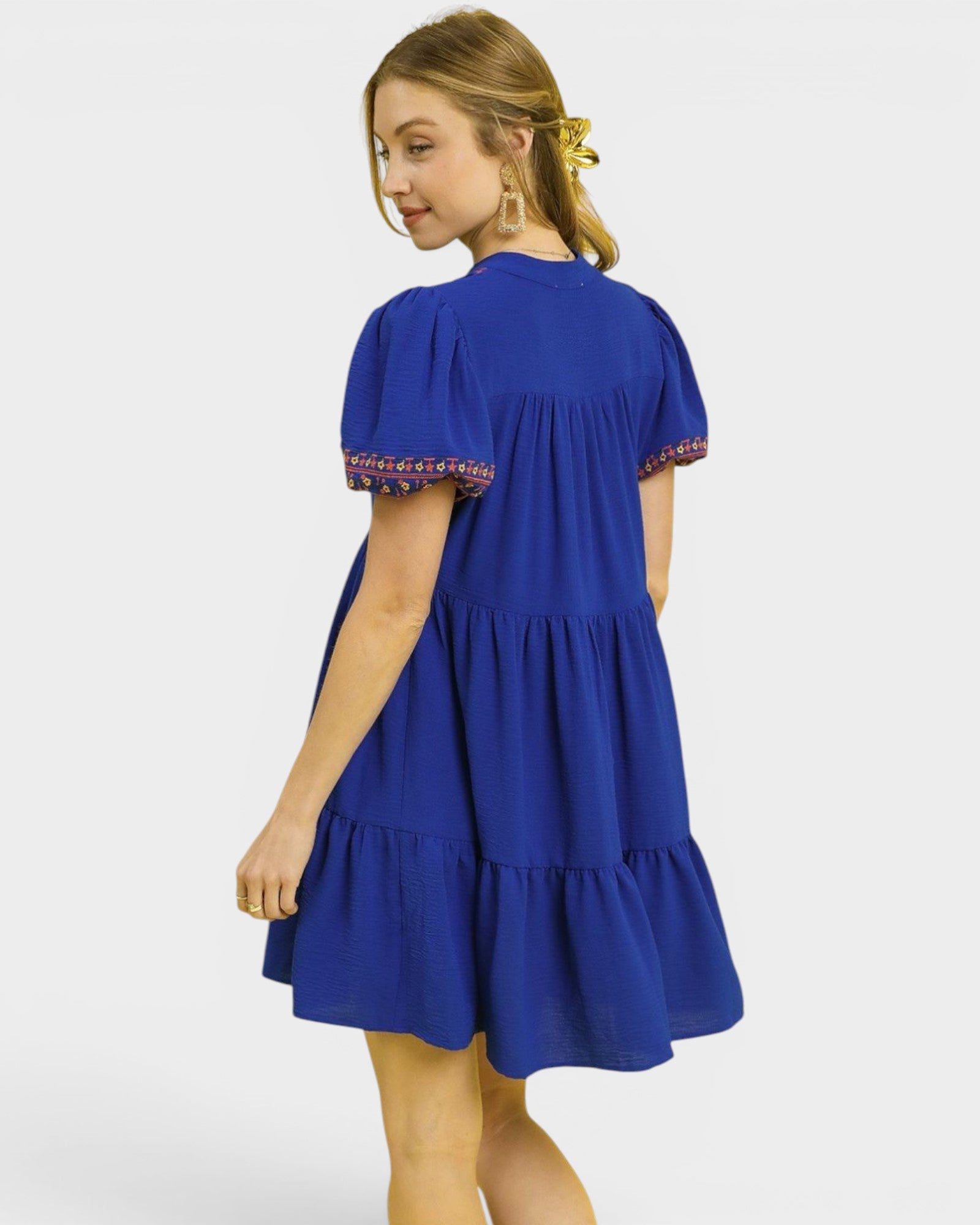 Woman wearing a blue dress with patterned sleeves on a white background