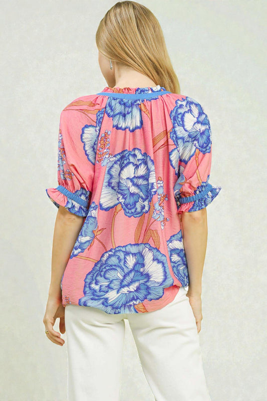 Woman wearing a colorful floral blouse with a plain background