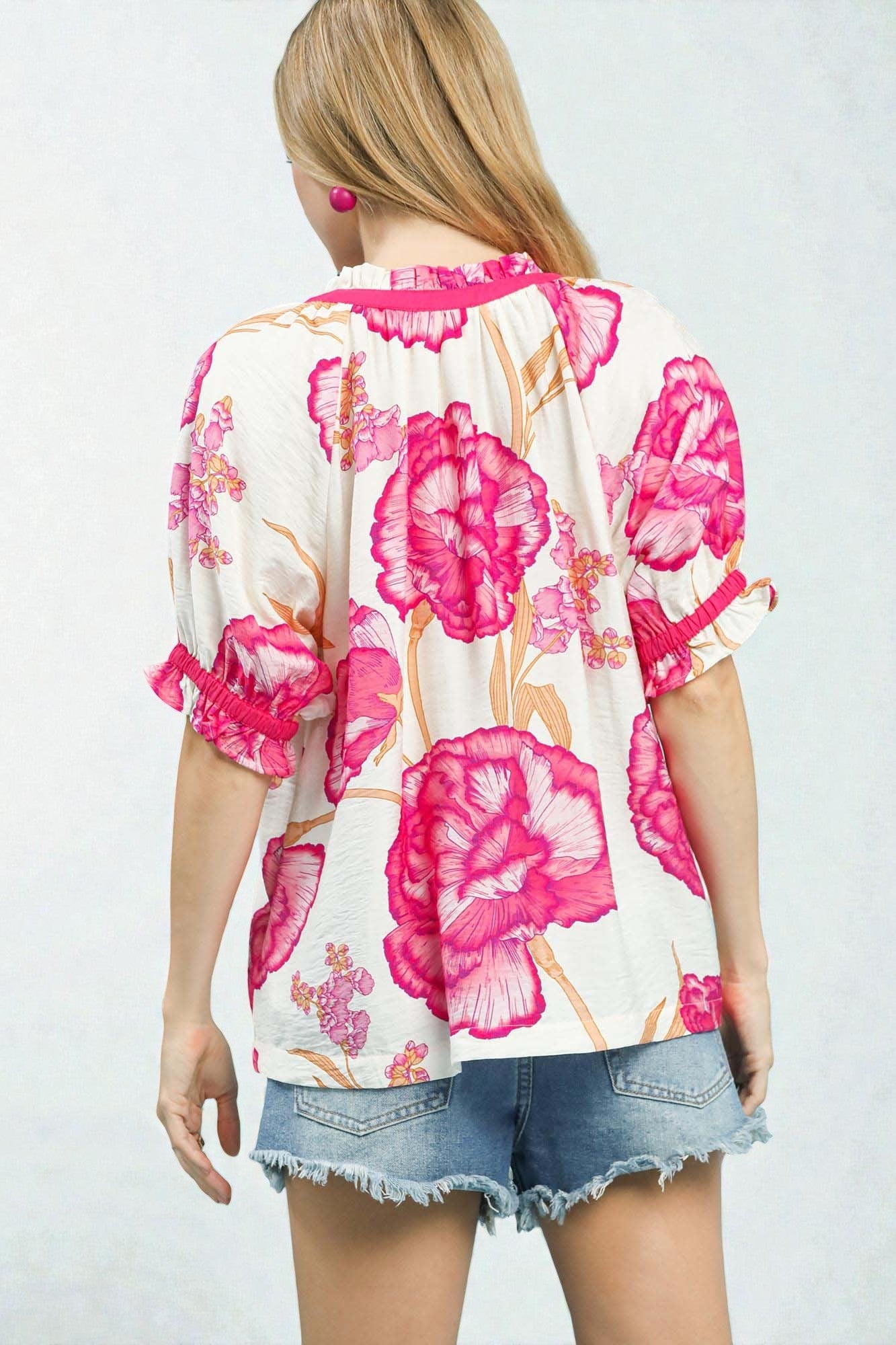 Woman wearing a floral kimono-style top with pink flowers on a white background