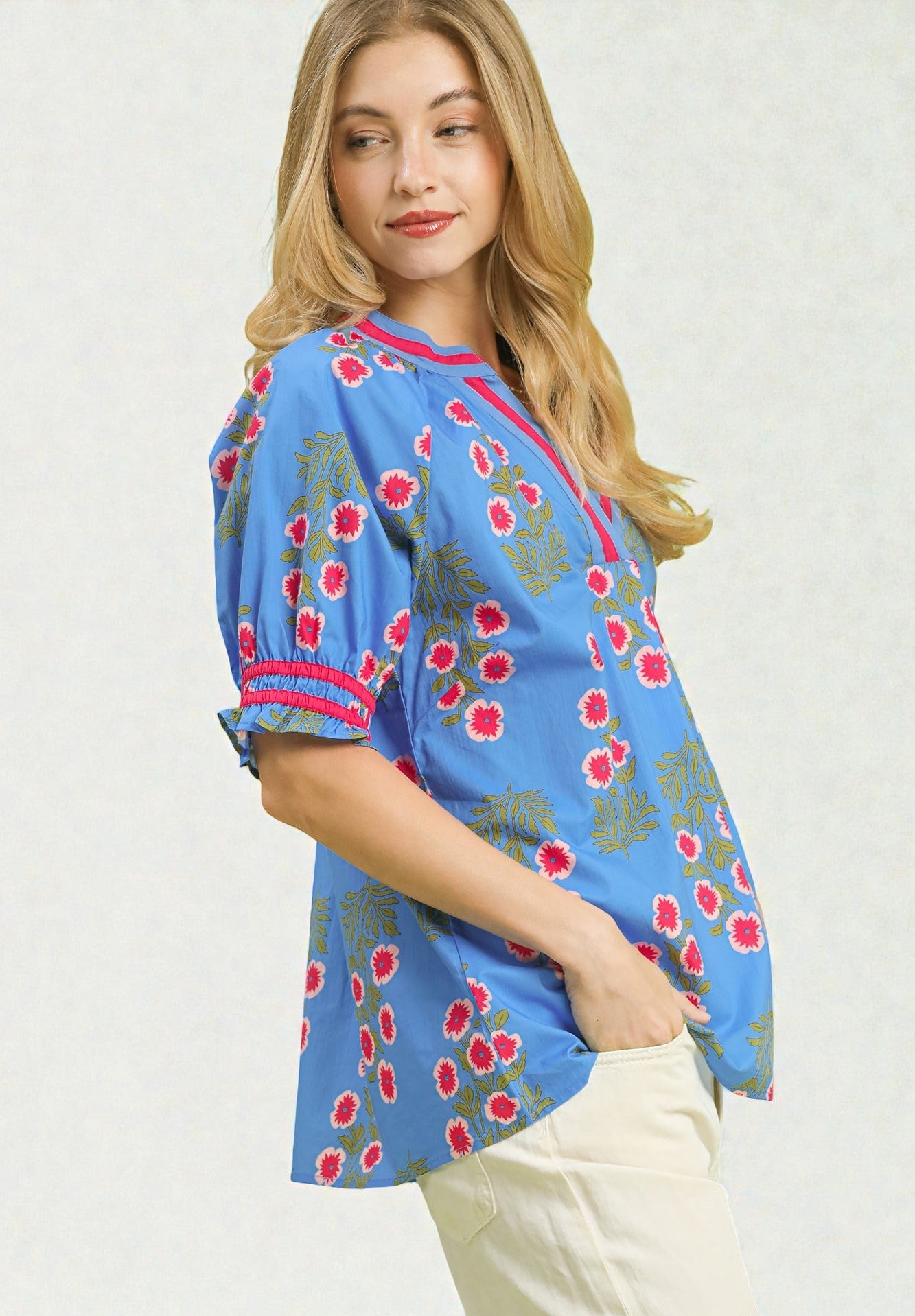 Woman wearing a blue floral blouse with red accents on a white background