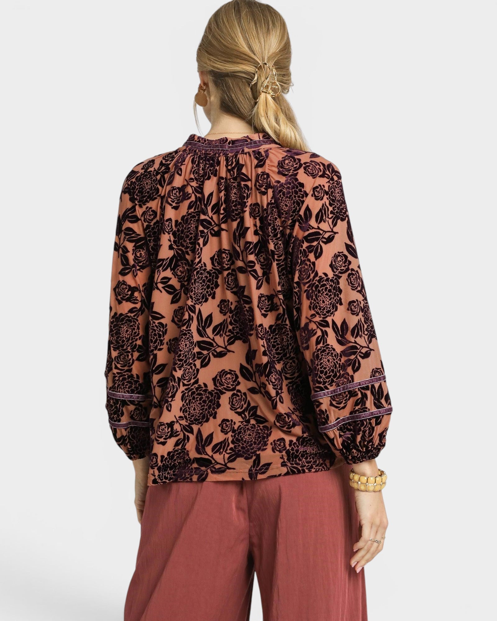 Person wearing a floral blouse and pants on a white background