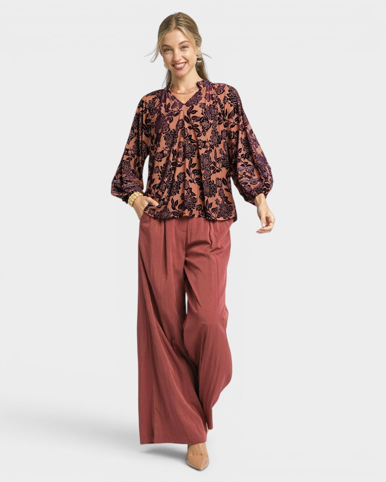 Woman wearing a patterned top and wide-leg pants on a white background