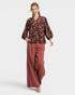Woman wearing a patterned top and wide-leg pants on a white background