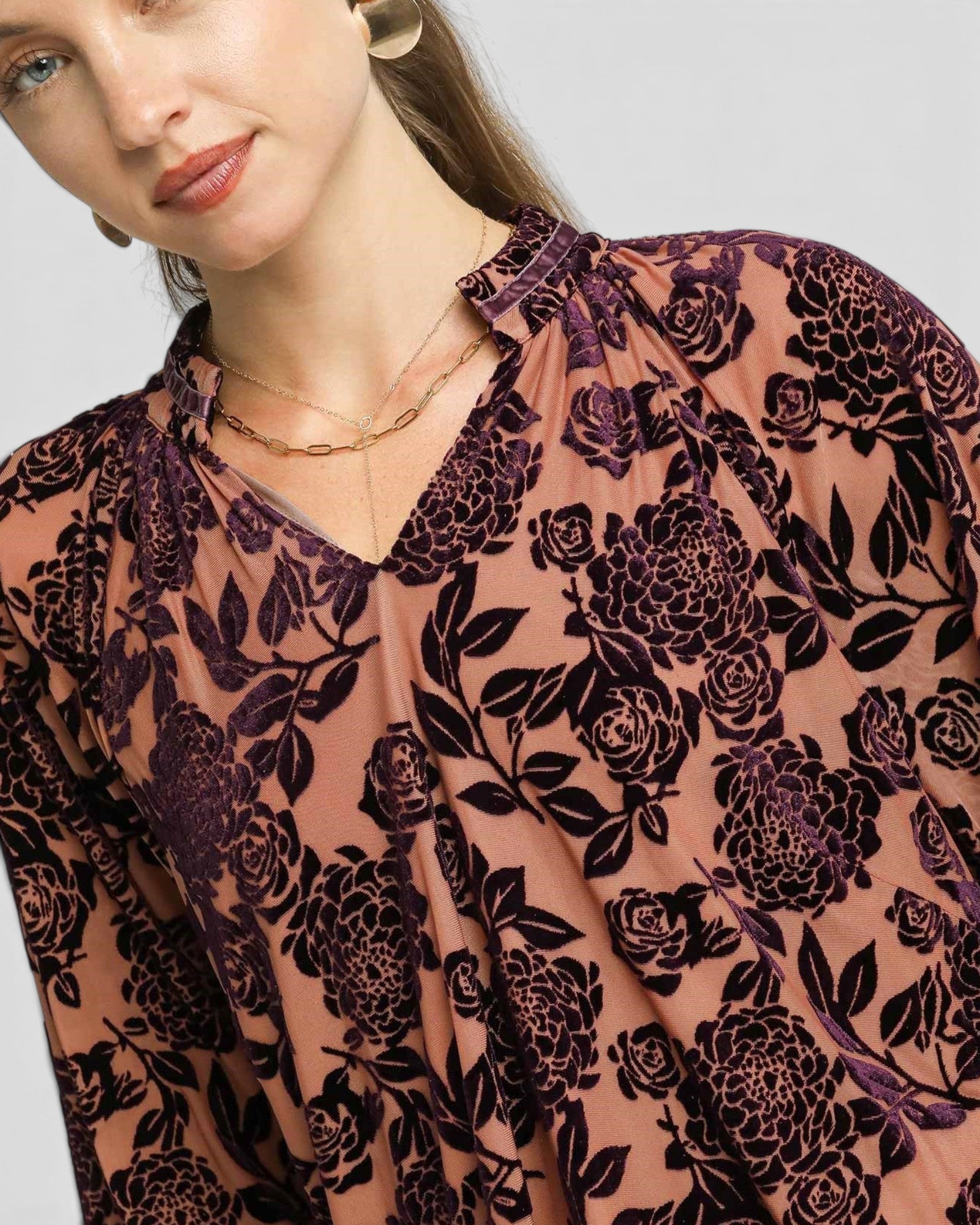 Woman wearing a floral patterned blouse with a plain background