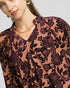Woman wearing a floral patterned blouse with a plain background