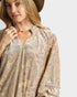 Woman wearing a beige floral blouse with a plain background