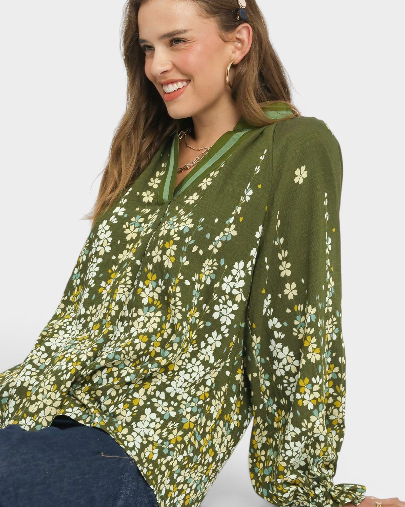 Woman wearing a green floral blouse against a white background