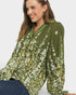 Woman wearing a green floral blouse against a white background