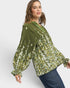 Woman wearing a green floral blouse against a white background