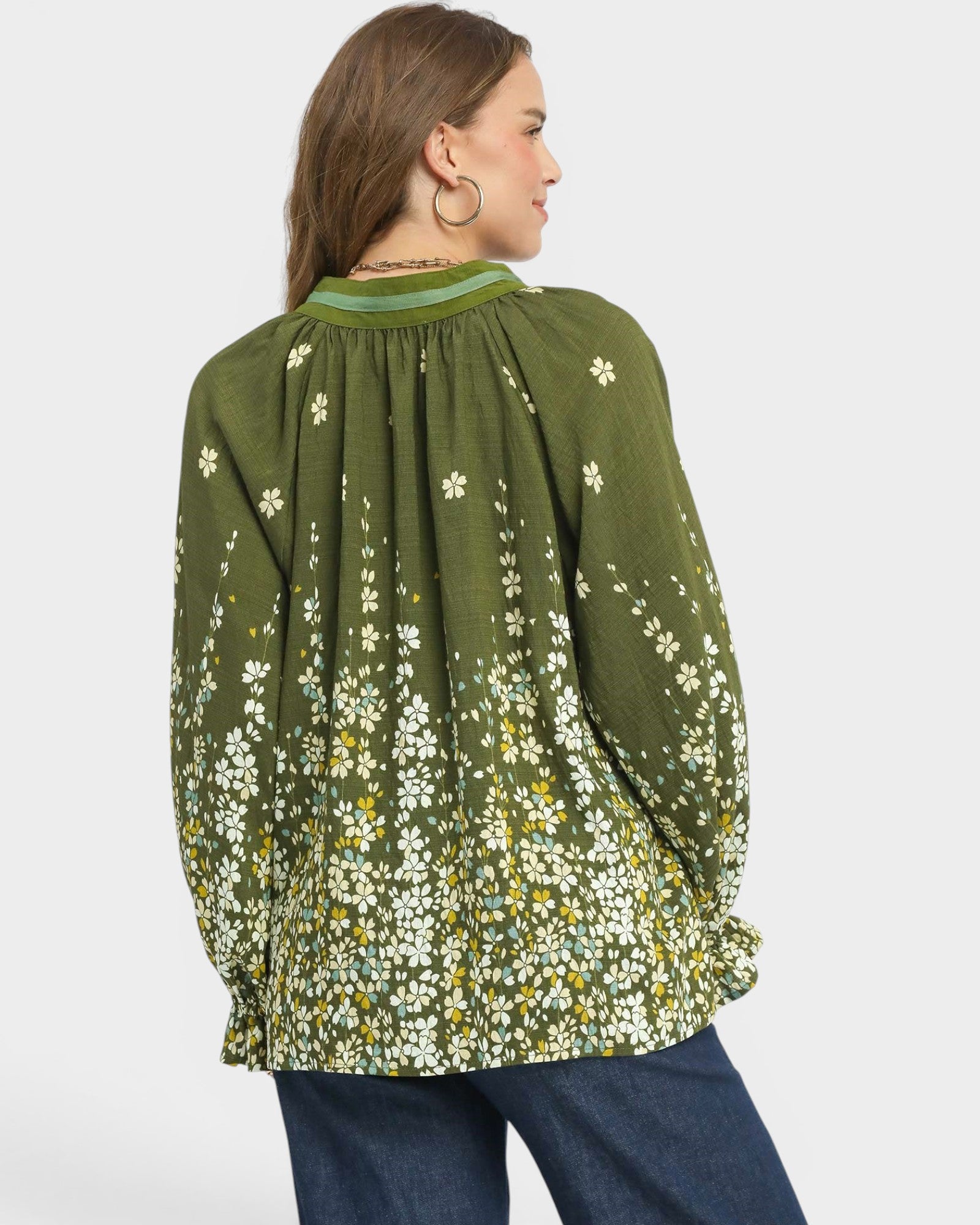 Woman wearing a green floral blouse with a plain background