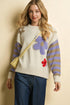 Woman wearing a colorful sweater with floral patterns on a beige background