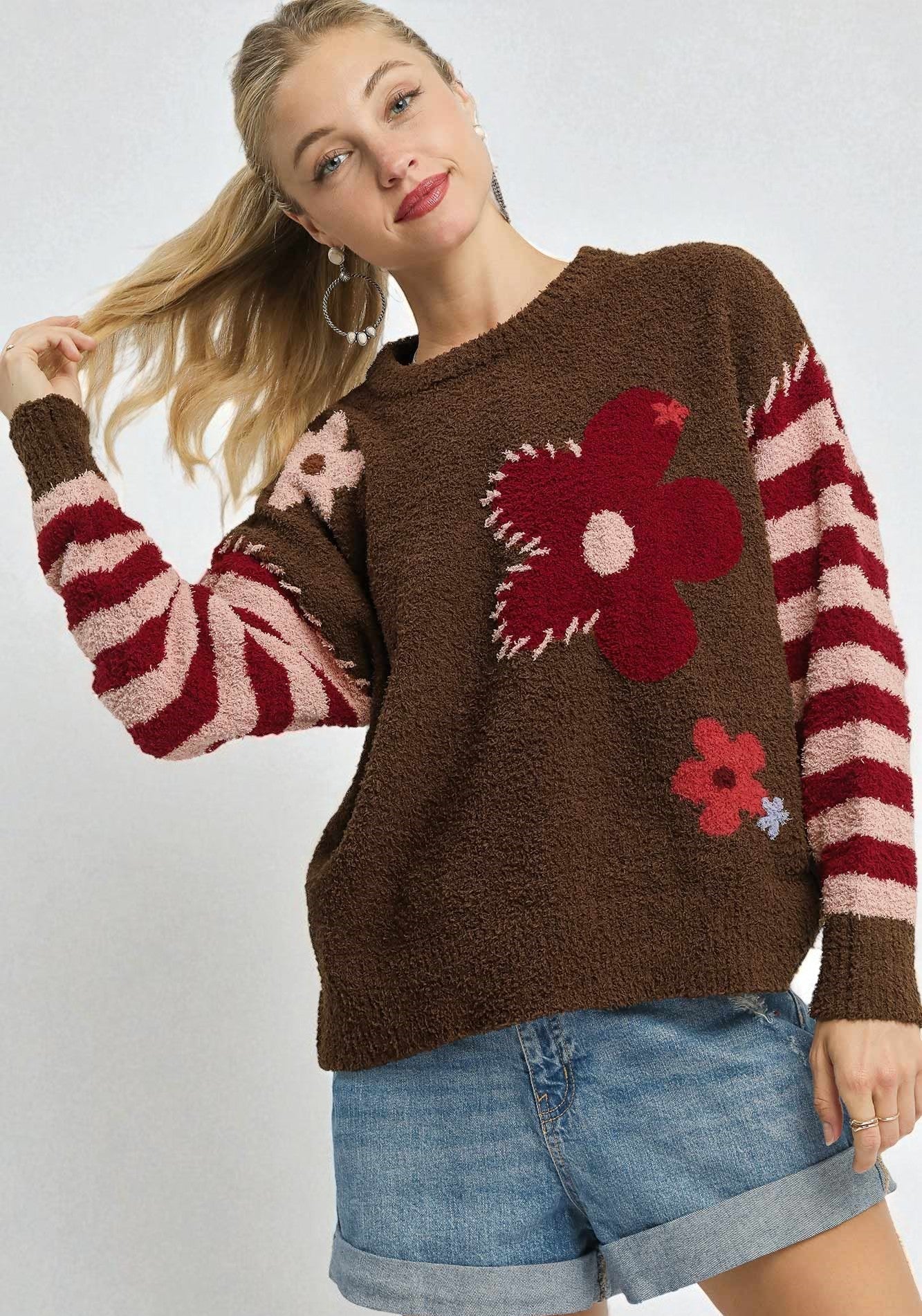 Woman wearing a brown sweater with floral patterns on a white background
