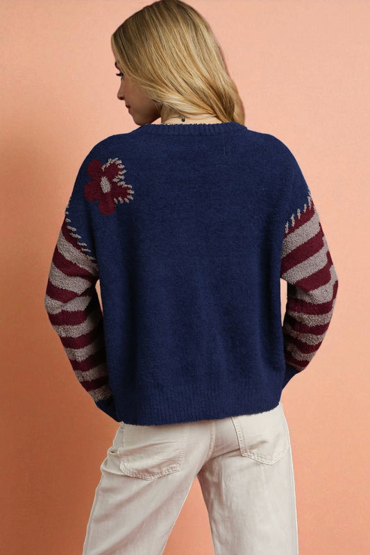 Person wearing a blue sweater with red and white pattern on a peach background