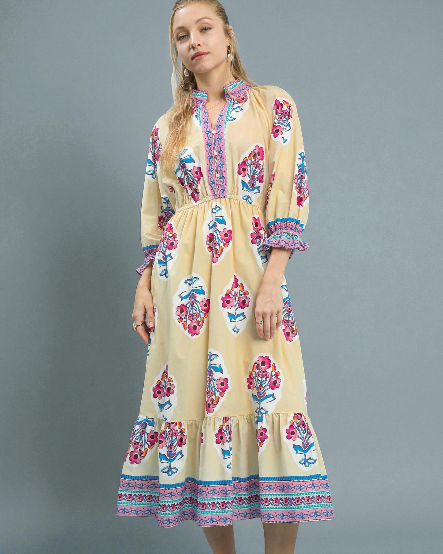 Woman wearing a yellow dress with floral patterns on a gray background