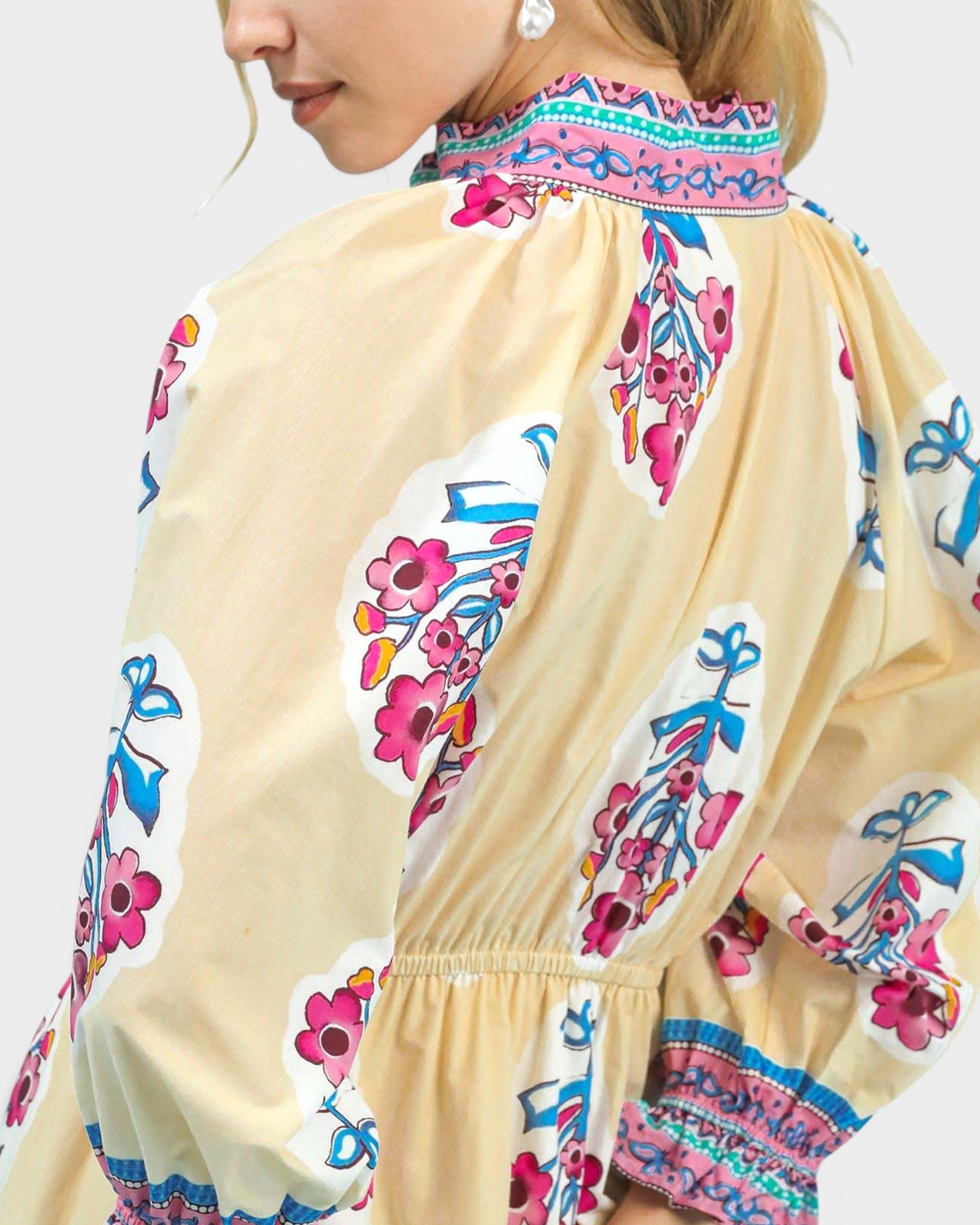 Beige dress with colorful floral embroidery on a plain background