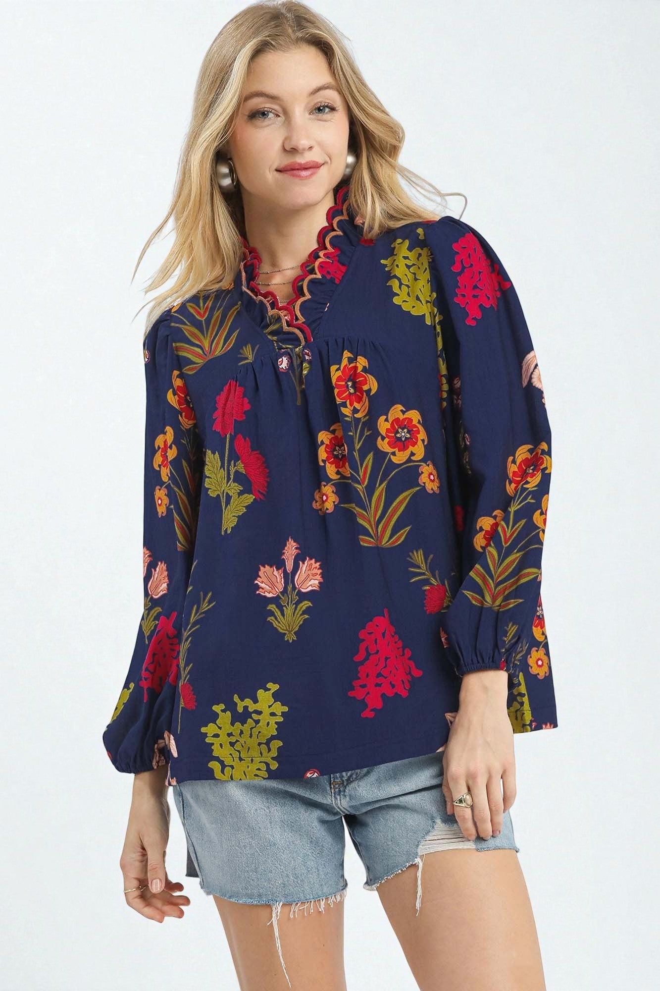 Woman wearing a navy blue blouse with colorful floral patterns on a white background