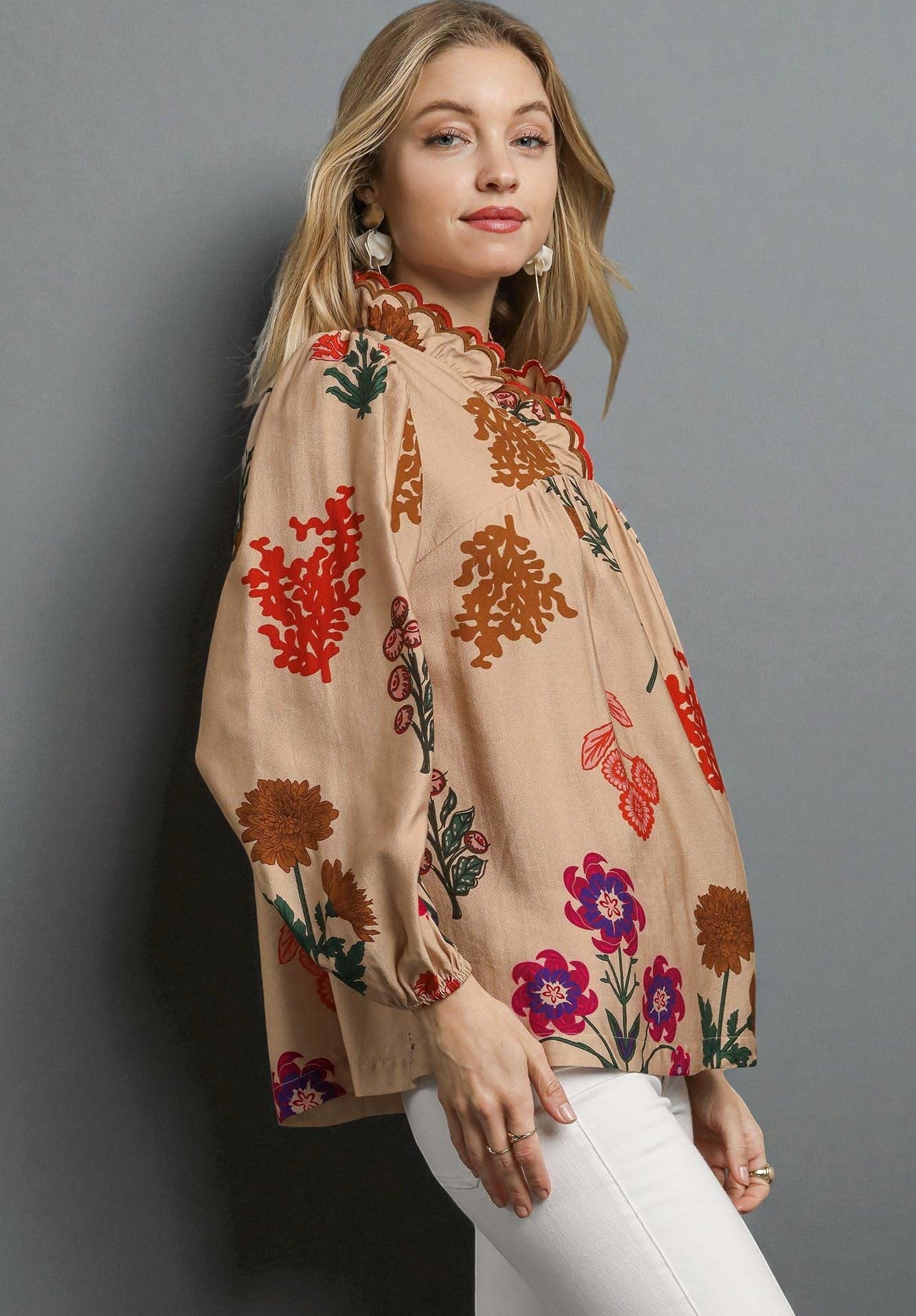 Woman wearing a beige blouse with colorful floral patterns against a gray background