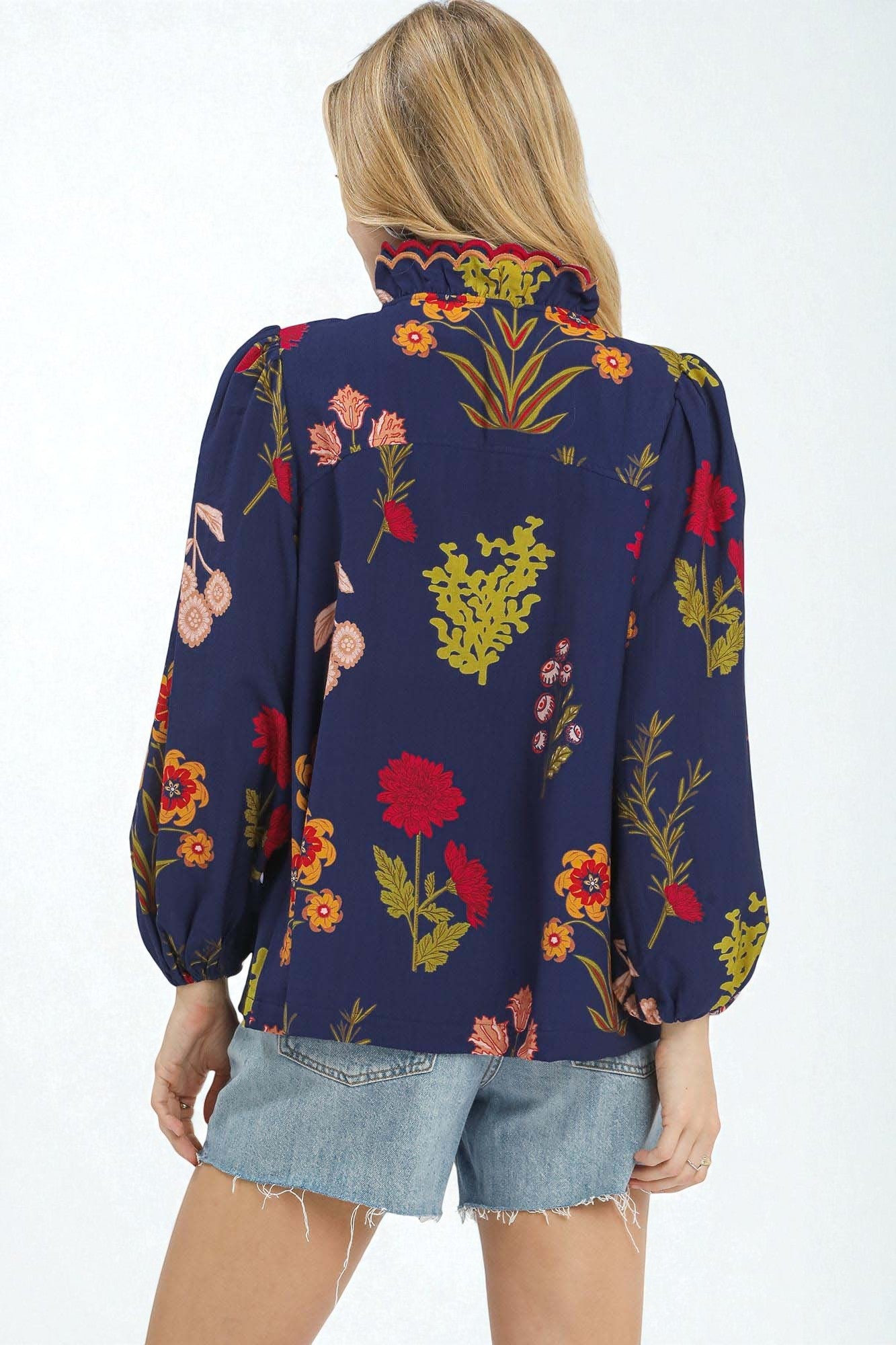 Person wearing a navy blue blouse with colorful floral patterns on a white background
