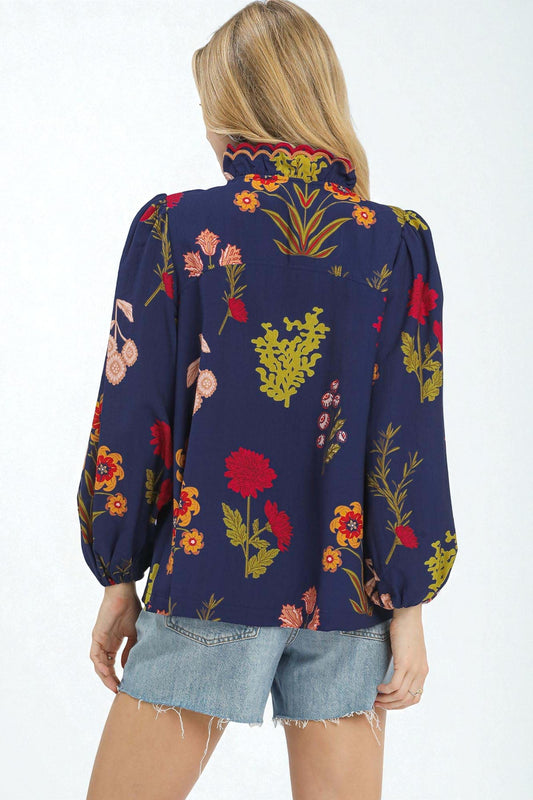 Person wearing a navy blue blouse with colorful floral patterns on a white background