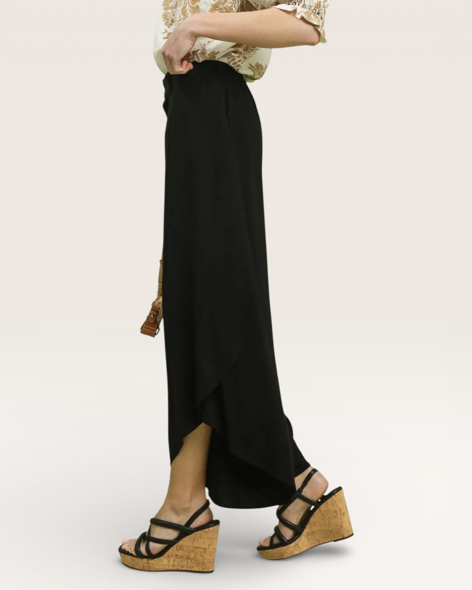 Person wearing a black wide-leg pants with a plain background