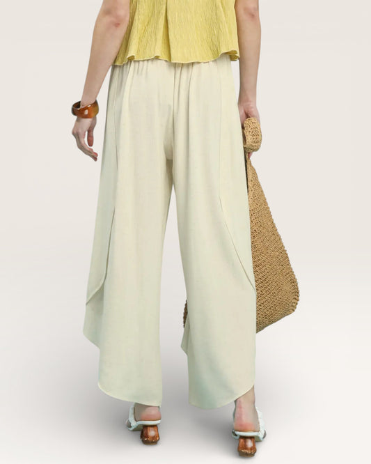 Person wearing a yellow top and light green wide-leg pants on a plain background