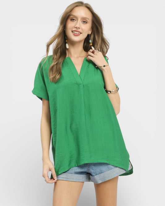 Woman wearing a green blouse and denim shorts on a white background