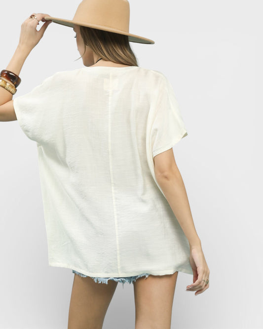 Person wearing a white oversized shirt and beige hat on a plain background