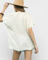 Person wearing a white oversized shirt and beige hat on a plain background