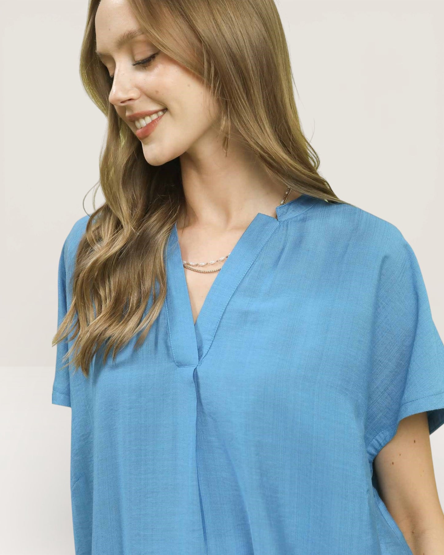 Woman wearing a blue top against a plain background