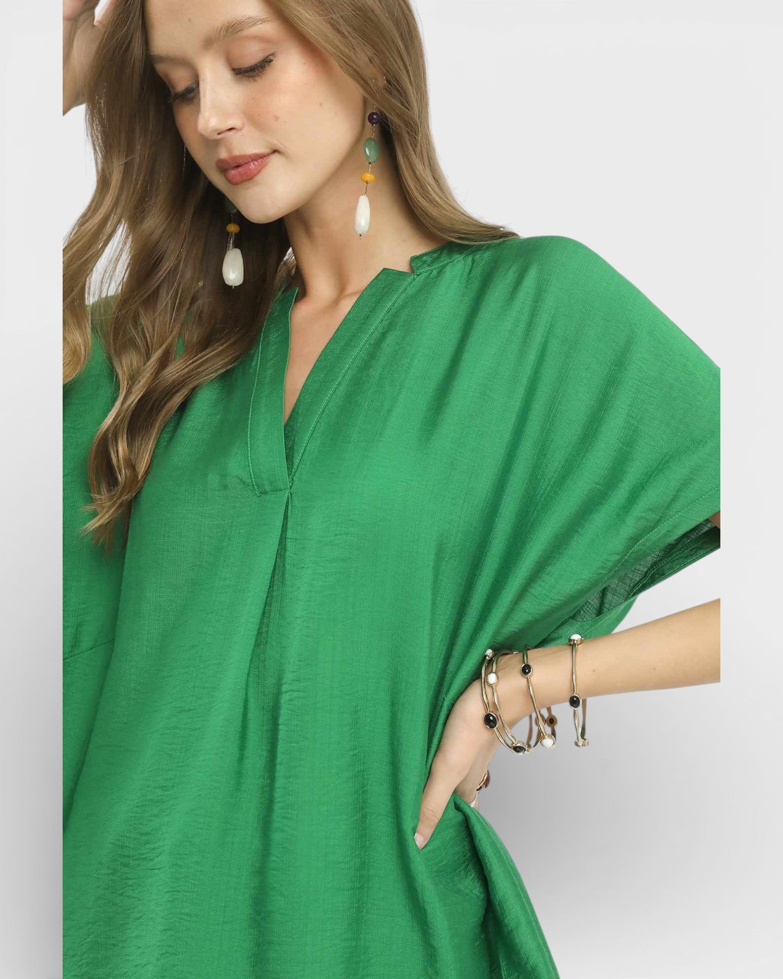 Woman wearing a green dress with jewelry on a plain background