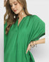 Woman wearing a green dress with jewelry on a plain background
