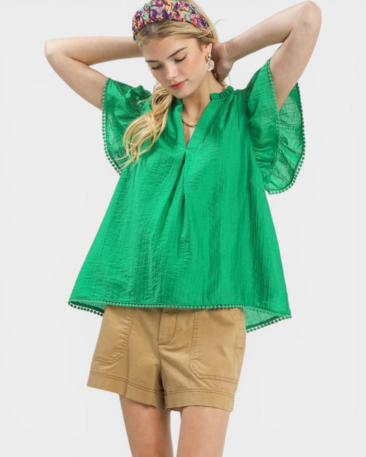 Woman wearing a green blouse and beige shorts on a white background