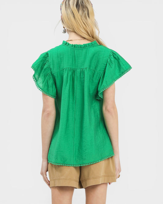 Green blouse with ruffled sleeves worn by a person on a white background