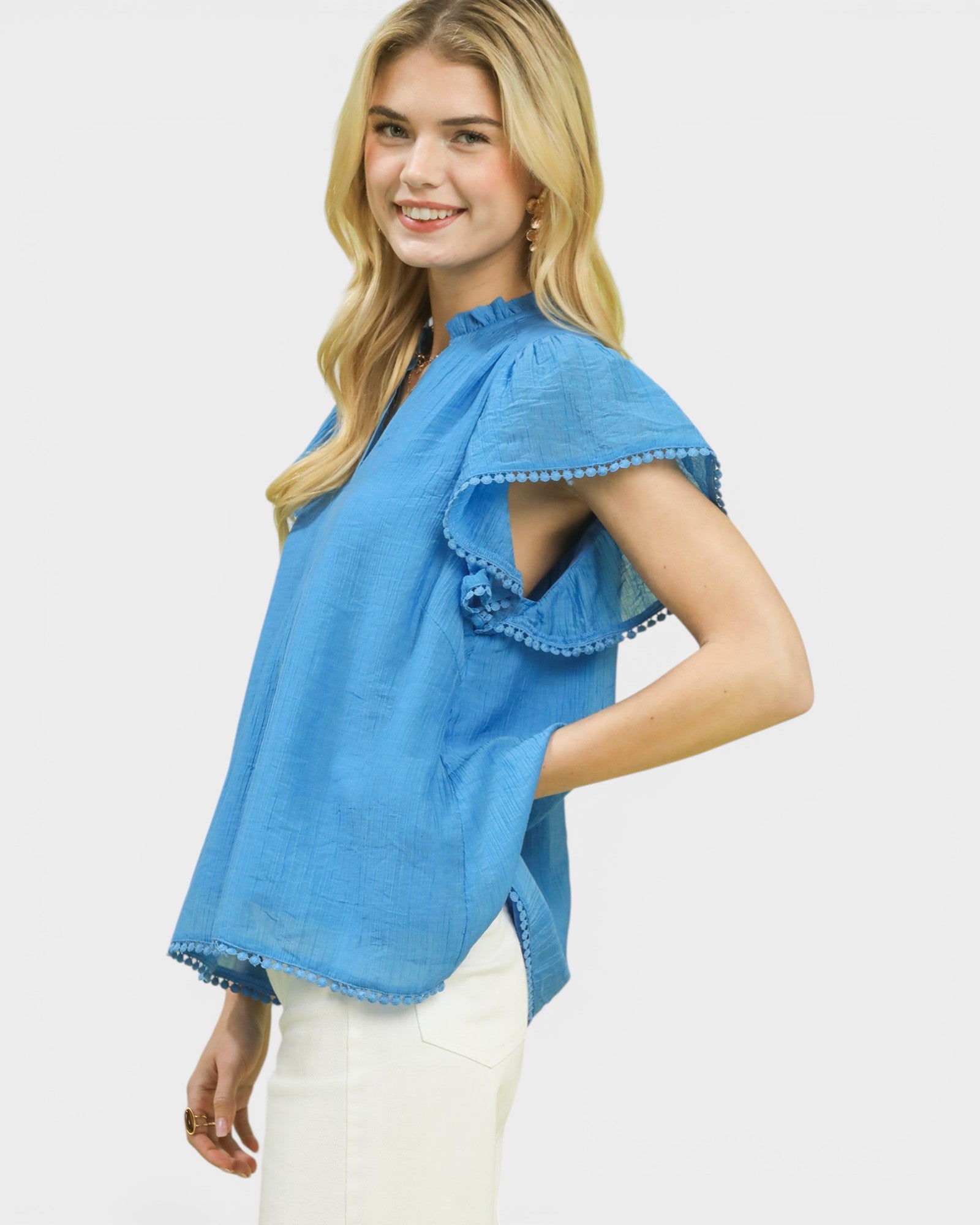 Woman wearing a blue top with ruffled sleeves on a white background