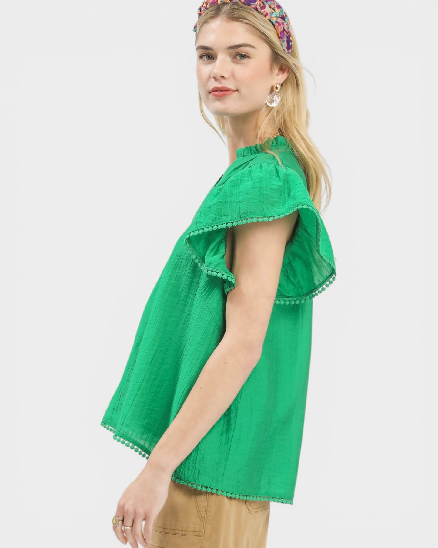 Woman wearing a green top with ruffled sleeves on a white background